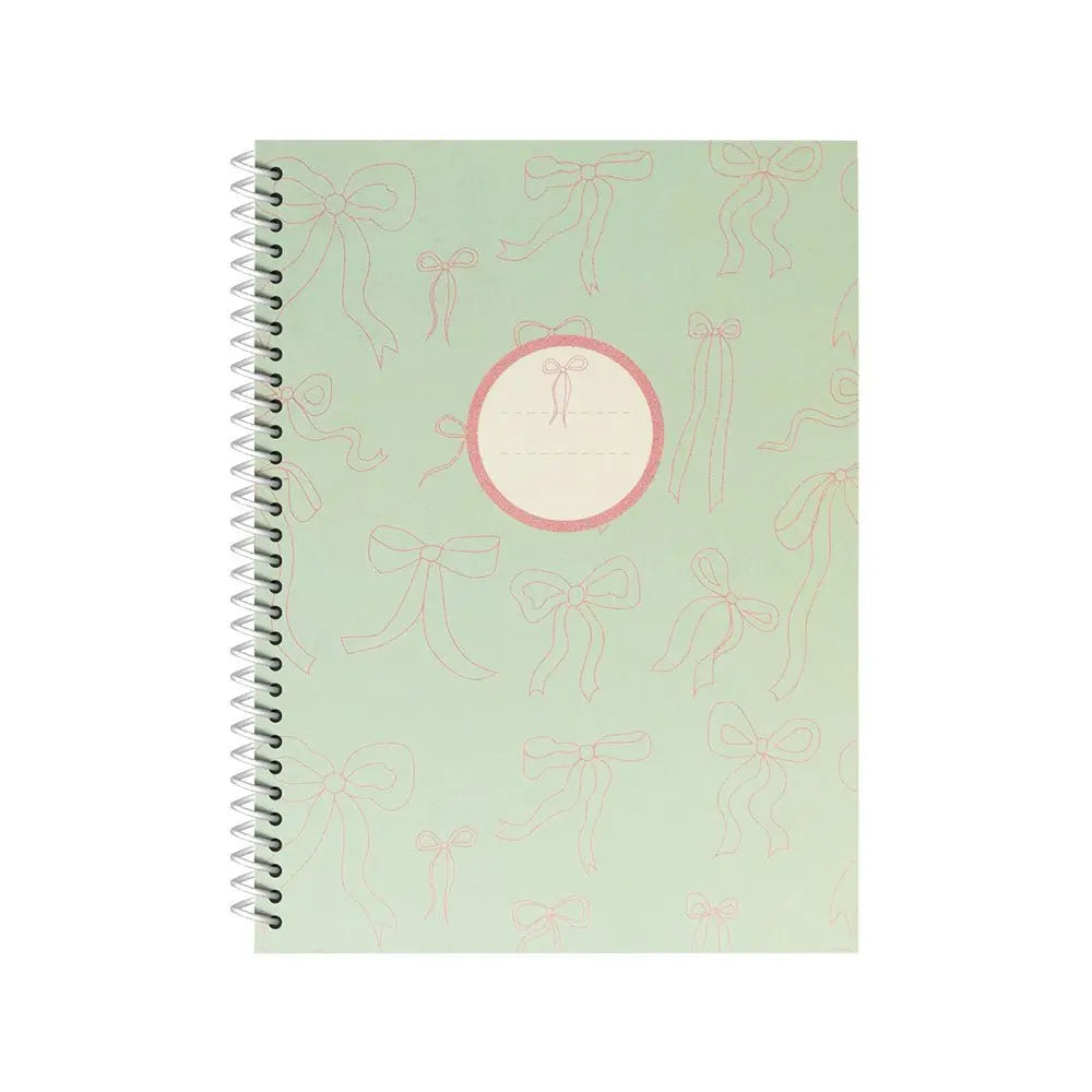 Caderno espiral A4 pautado LACES verde da marca Ancor com 80 folhas, visto de frente sobre mesa.